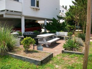 A wide shot of the exterior of a villa shows a lounging area and a car parking space under the building.