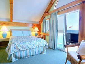 A room with a bed and lampshade on the bedside with balcony access.
